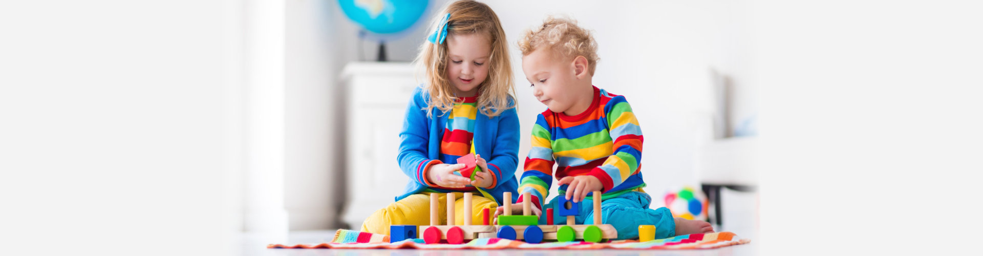 two children playing on the floor with their toys